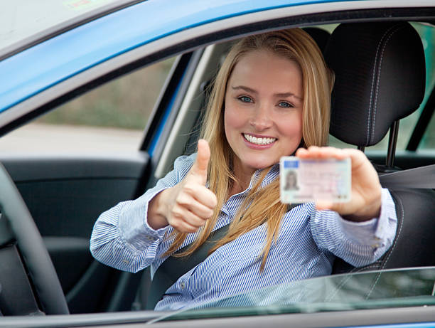 Attractive woman in car showing her drivers license stock photo