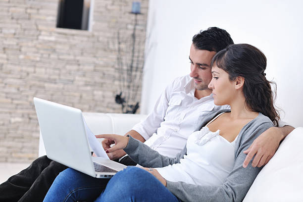 istock Couple relaxing together at home looking at a laptop 141232719