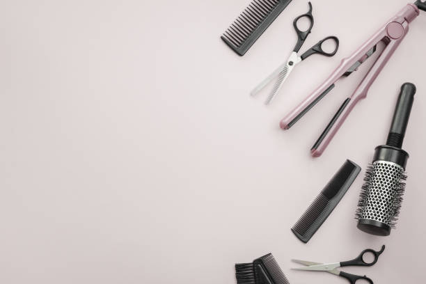 istock Scissors, combs, brushes and a hair straightener on a pale pink background. 1412327807