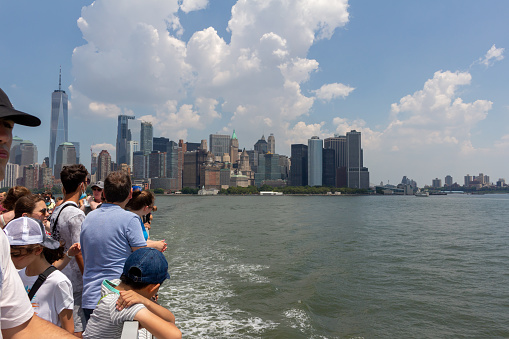 New York City, New York, USA - July 20, 2022: Daytime view of ferry boat passengers observing the Manhattan skyline from the Upper New York Bay.
