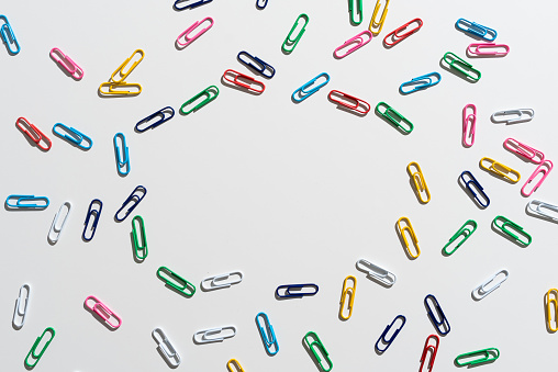 A closeup shot of colorful paperclips on a dark table in the office