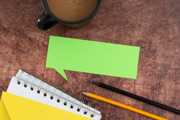 istock Color Speech Bubble With Spiral Notebook, Pencils And Coffee Mug Placed On Wooden Table. It Is Showing New Ideas And Important Strategies For Business Growth. 1412329254