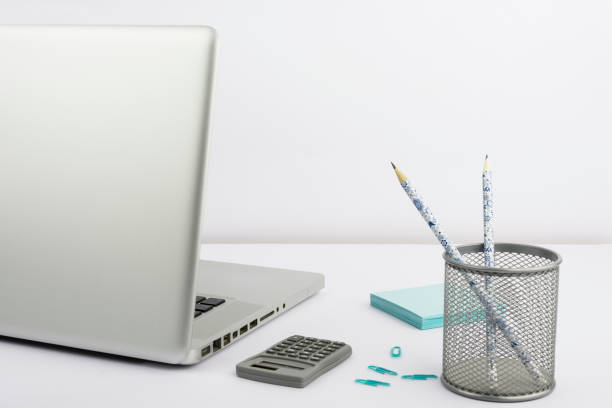 Lap Top, Case With Pencils, Calculator, Paperclips And Notes Placed On Desk