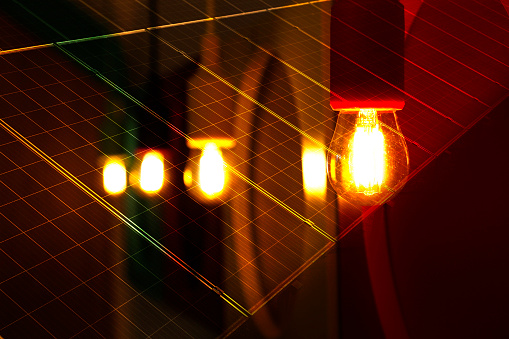 detail of several light bulbs lit in yellow color and warm tone, dark background - plates with cells for capturing solar energy