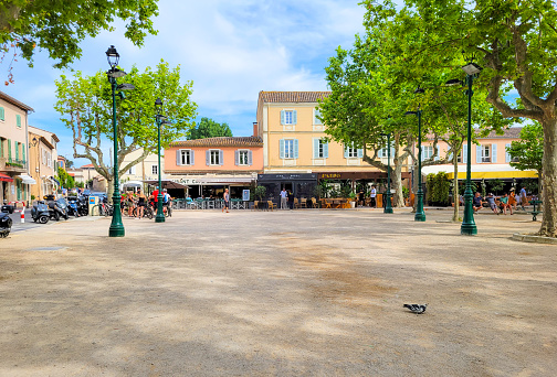 Sidewalk cafes border the Place des Lices public park, also known as Place Carnot, in the historic center of Saint-Tropez, France, along the Provence, Cote d'Azur and Riviera region of Southern France along the Mediterranean.