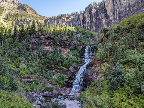 A waterfall near Telluride, Colorado, surrounded by mountain cliffs and pine trees