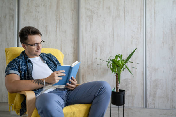 istock one caucasian man read book at home while sitting in chair 1412345695
