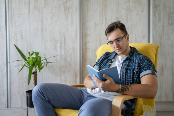 istock one caucasian man read book at home while sitting in chair 1412345699