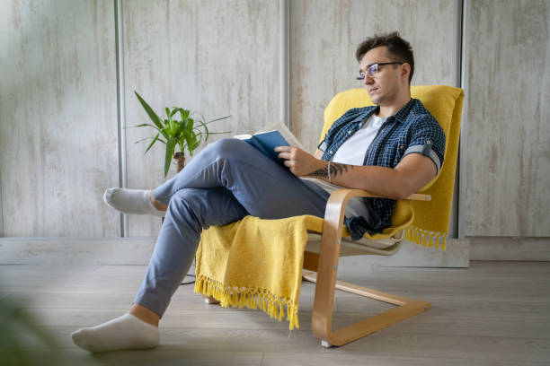 istock one caucasian man read book at home while sitting in chair 1412346515