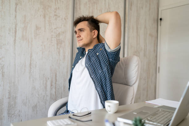 istock young man stretching at work while sitting at desk having back pain 1412346541