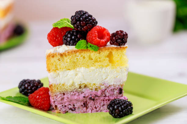 Peace of sponge cake with fresh raspberry and blackberry on wooden table.
