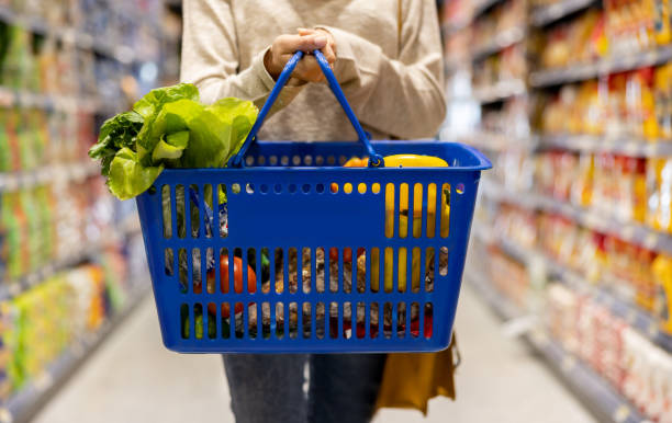 Woman at the supermarket carrying a shopping basket stock photo