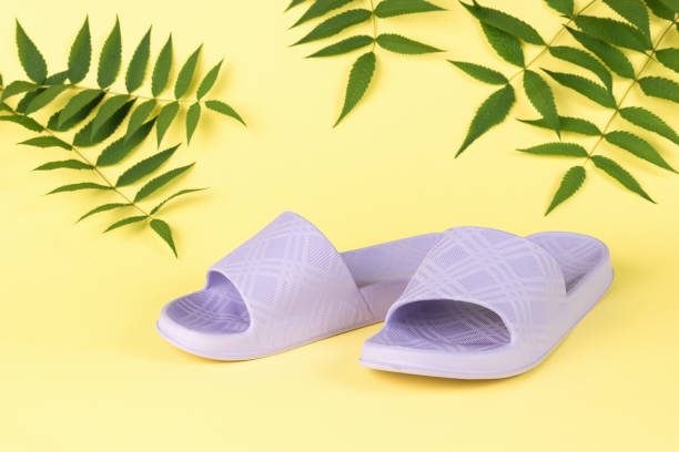 istock Purple rubber flip-flops on a yellow background and leaves. 1412354311