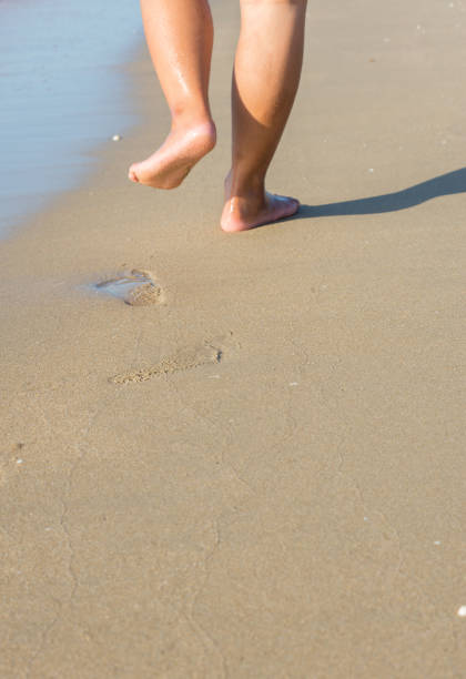 istock Legs and feet walk alone on the beach on vacations. 1412361856