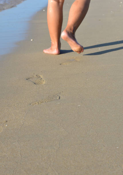 istock Legs and feet walking on the beach. 1412361860