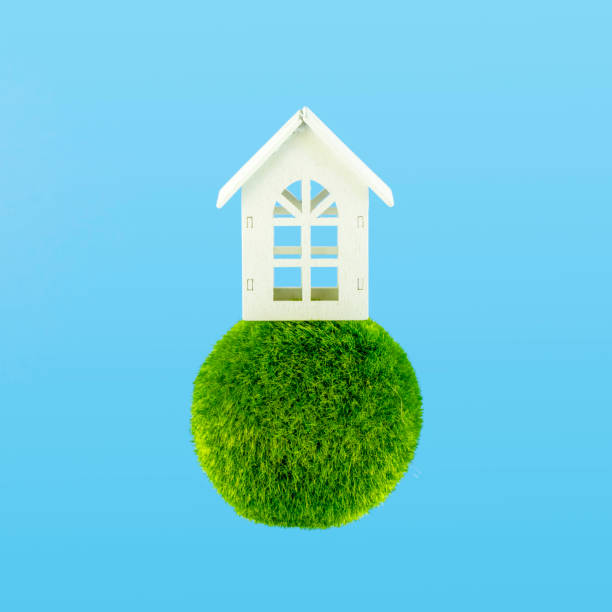 Wooden white house on a sphere green grass with sky blue background. stock photo