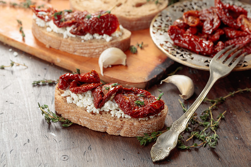 Bruschetta with ricotta, sun-dried tomatoes, and thyme. Traditional Mediterranean snack.