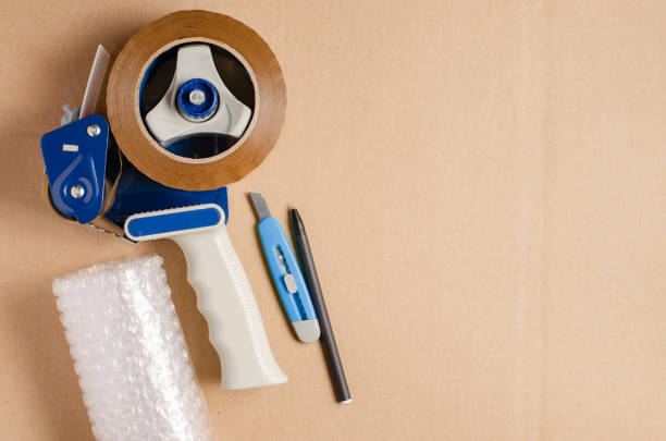 Tools for packaging goods in an online store. Brown cardboard background. Copy space.