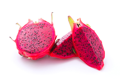 Close up of a basket of dragon fruit on a fruit and vegetable stall.  Of the pieces of fruit is cut in half.