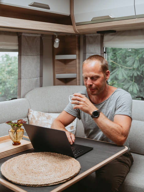 istock Man working on laptop in caravan camping remote working 1412378490