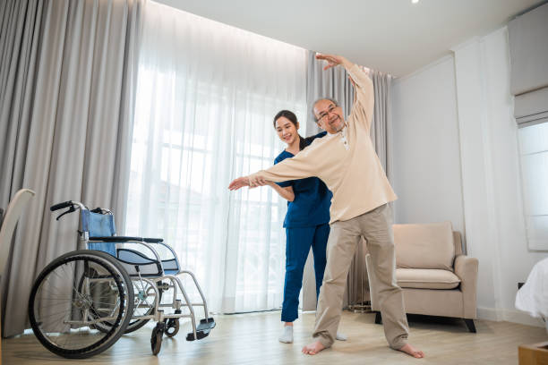 istock Old senior man enjoys training with physiotherapist for outstretched arms at home 1412378680