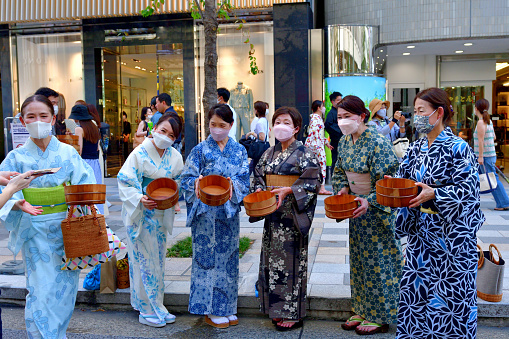 Tokyo, Japan-August 1, 2022\nSprinkling of water in Ginza, Tokyo, in order to cool down the summer heat, utilizing recycled waste water. Women in yukata are posing for photo after the event was over, by showing an empty water keg. \nThis event, called Uchimizu in Japanese, takes place on the last weekend of July, or first weekend of August, annually, with many men and women turning up in yukata, traditional Japanese summer kimono.\nAfter 2 years' absence due to VOVID-19 pandemic, the event was resumed this year on a limited scale. People still wear protective mask face due to the pandemic.