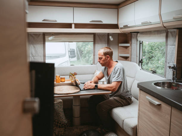 istock Man working on laptop in caravan camping remote working 1412380118