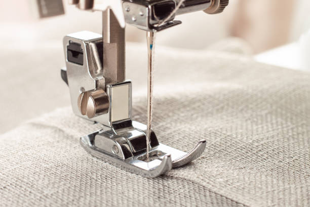 Modern sewing machine presser foot and item of clothes. Sewing process, handmade, hobby, business Modern sewing machine presser foot with linen fabric and thread, closeup, copy space. Sewing process clothes, curtains, upholstery. Business, hobby, handmade, zero waste, recycling, repair concept seamed stock pictures, royalty-free photos & images