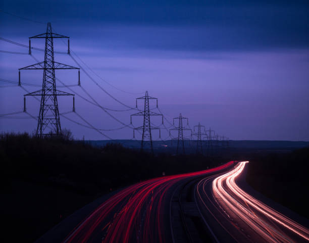 Trilhas leves da Rodovia M40 e cabos de energia ao anoitecer, Oxfordshire, Inglaterra, Reino Unido, Europa - foto de acervo