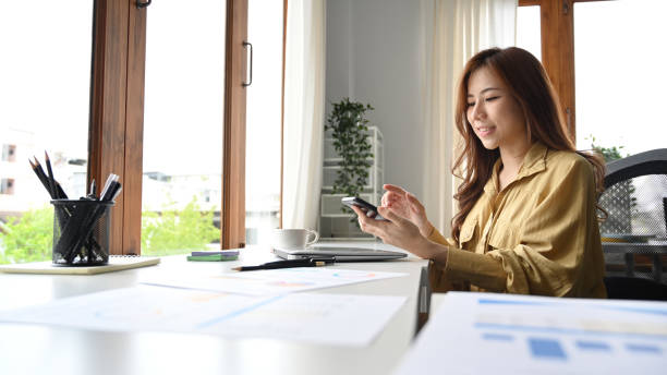 istock Charming businesswoman sitting in bright modern office and using mobile phone during break. 1412383903