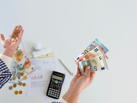 a man's hand is holding a series of euro banknotes against a white background. Only in the middle there is a small area that is sharp