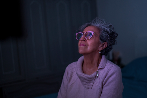 Elderly woman between 60-70 years old resting at home watching TV