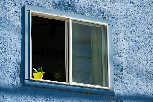 Yellow flowerpot in a window of a blue house