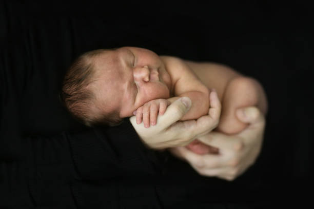 istock tender newborn baby on a dark background 1412386843