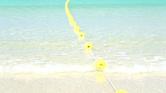 Yellow marker swim area buoys blue sea water sunny summer. Yellow floating buoy wave water foamy over ocean.