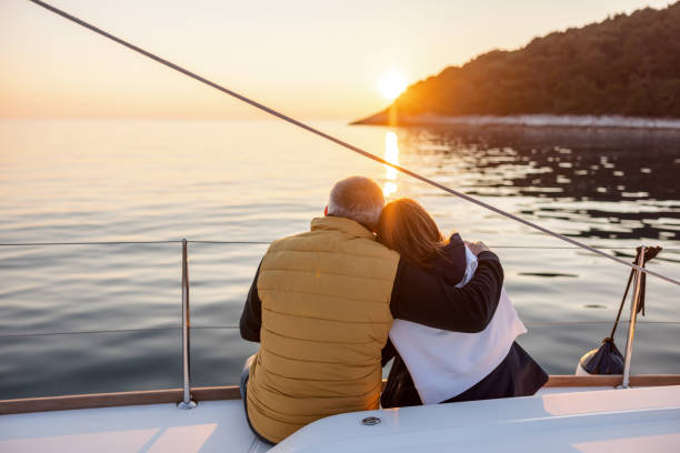 Lovely Mature Couple Hugging On A Yacht Cheerful wife and husband embracing each other when having quality time yachting together. sailing couple stock pictures, royalty-free photos & images