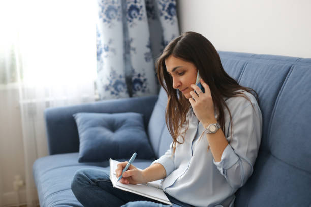 istock Beautiful woman talking on phone and writing 1412389152