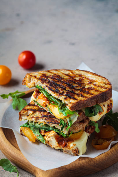Grilled sandwich with vegetables and mozzarella on wooden board. stock photo