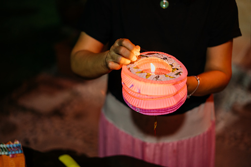 Image of an Asian Chinese senior woman preparing candle for lantern during mid autumn festival celebration
