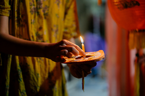 Image of an Asian Chinese woman preparing candle for lantern during mid autumn festival celebration