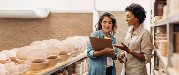 陶磁器店で議論をしている幸せな若いビジネスウーマン - potter small business pottery happiness ストックフォトと画像