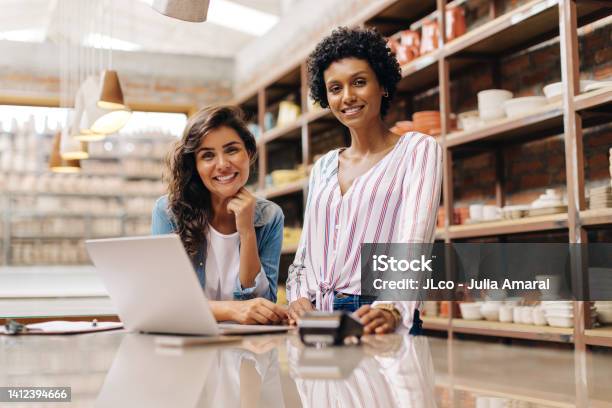 Cheerful Female Entrepreneurs Smiling At The Camera In Their Ceramic Shop Stock Photo - Download Image Now