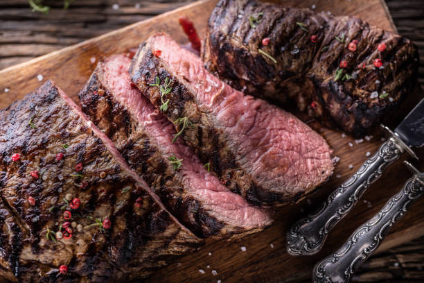 istock Grilled beef steak cut on a butcher board - Top of view. 1412396601