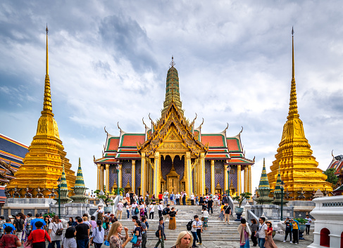 Bangkok, Thailand - September 9, 2019: tourists visiting the beautiful building of Wat Phra Kaew Temple of the Emerald Buddha, grand palace on the cloudy sky day, the most famous spot and must visit place and temple in Bangkok, Thailand from the front door