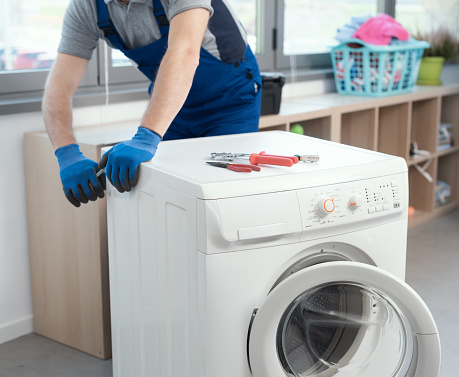 Professional repairman fixing a broken washing machine, home repair concept
