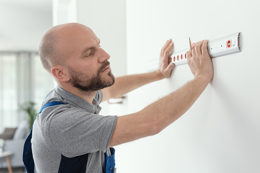Professional handyman making measurement using a bubble level, home improvement concept