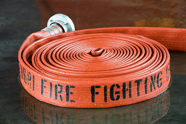A rolled up firehose on the wet floor in a firestation used by firefighters