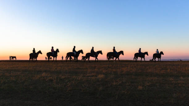 istock Horses Riders Silhouetted Dawn Sky Landscape 1412404897