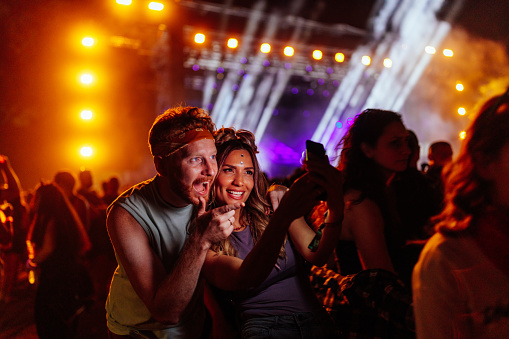 A joyful young Caucasian couple is dancing at a music festival day party.
