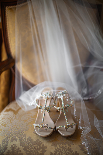 Wedding shoes with veil on vintage armchair.